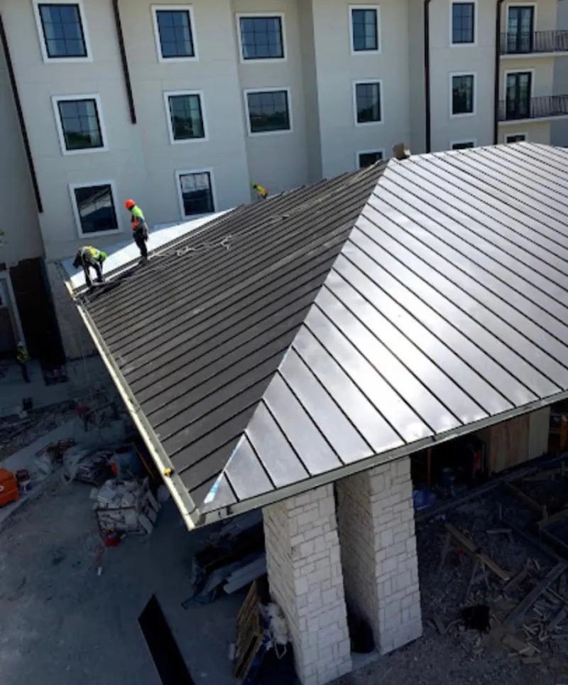 Crew installing standing seam metal roof panels on a commercial project in Nipomo